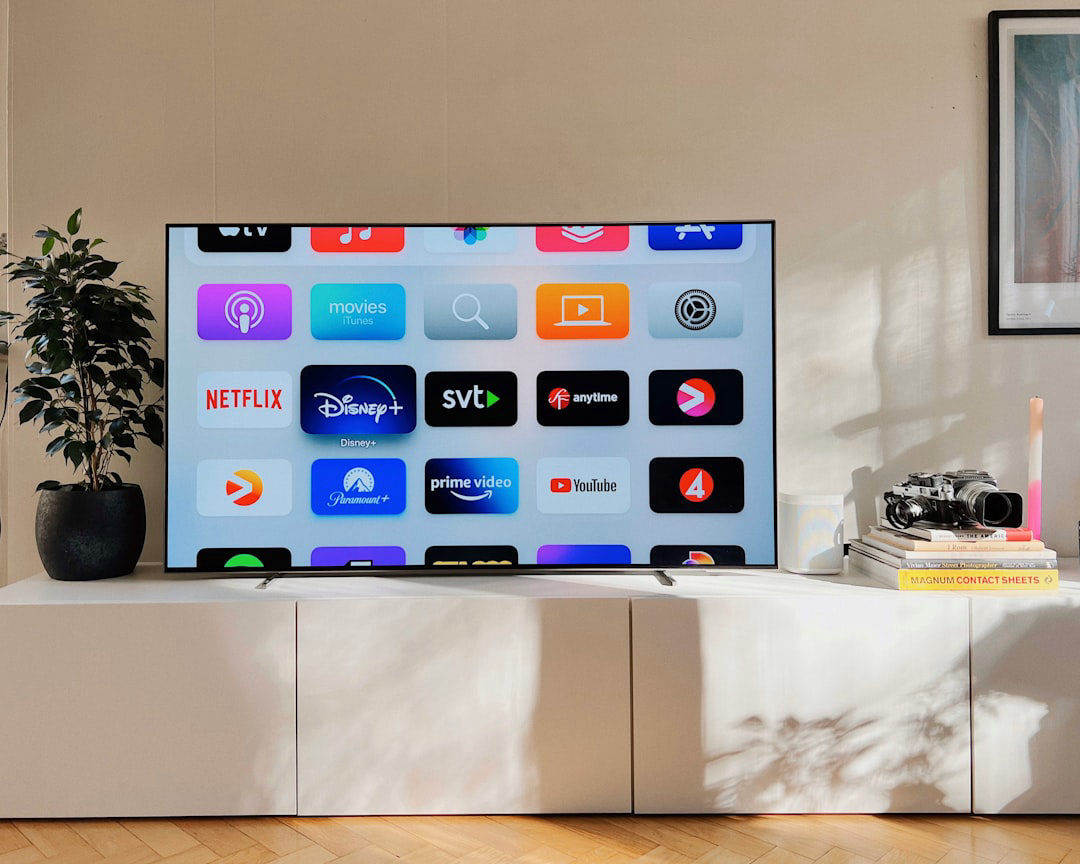 A large modern smart TV displaying streaming app icons in a clean, bright contemporary living room
