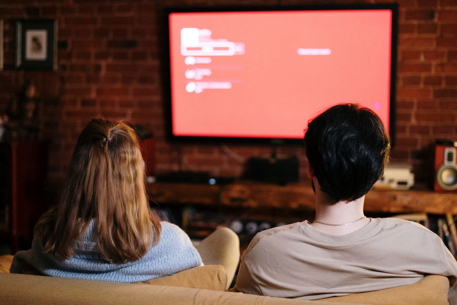 A couple relaxing on a sofa at home in the evening watching streaming TV