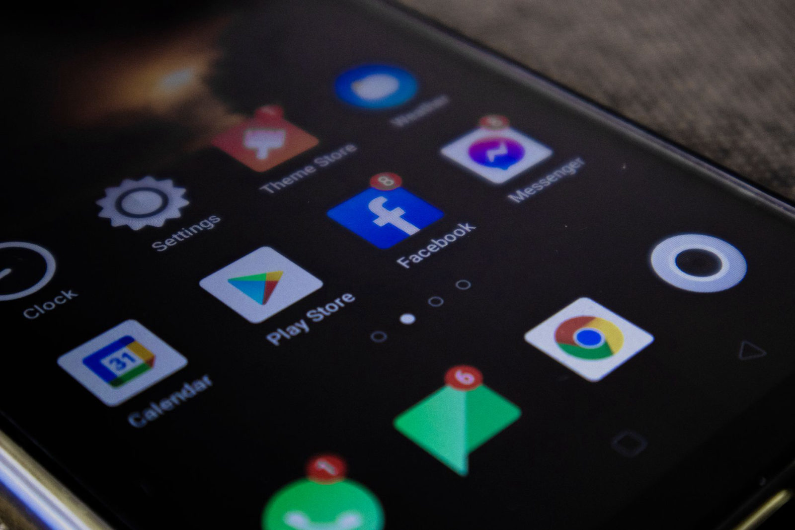 A smartphone screen displaying Google Play Store, Facebook, Chrome, and other apps — illustrating the google ads vs facebook ads decision for local business marketing budgets