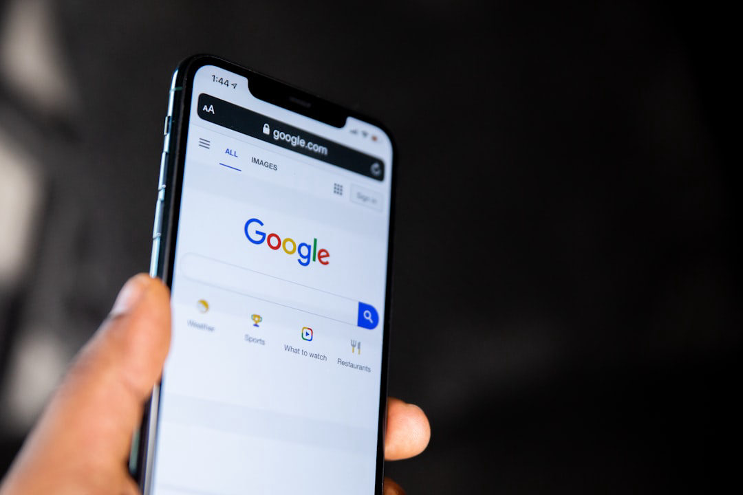 A hand holding a smartphone displaying the Google homepage, illustrating how to get more Google reviews by making the process mobile-friendly and accessible