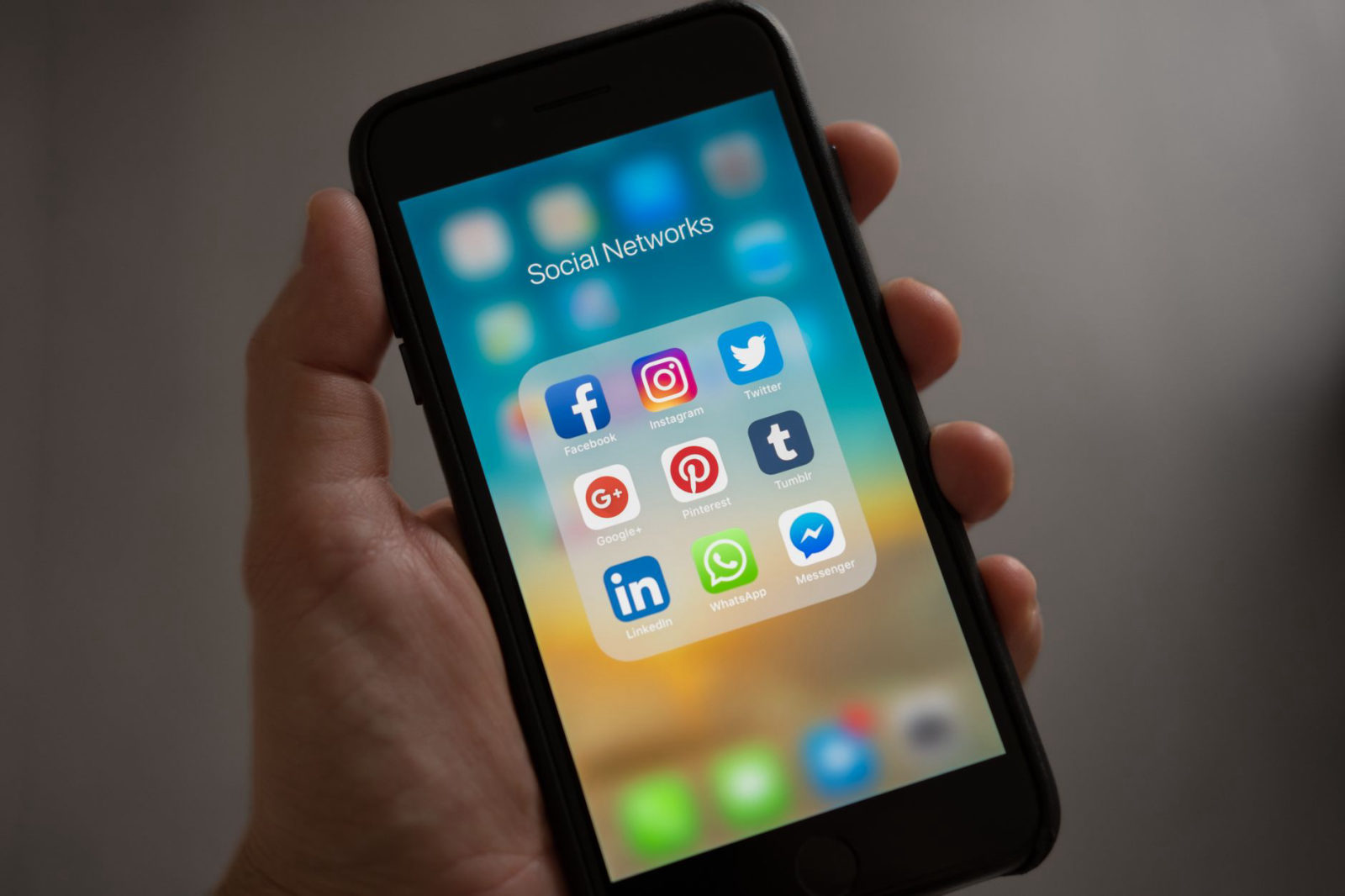 A hand holding a smartphone displaying social media app icons including Facebook, Instagram, and Twitter — illustrating the best time to post on Instagram and Facebook for local businesses in Santa Clarita CA