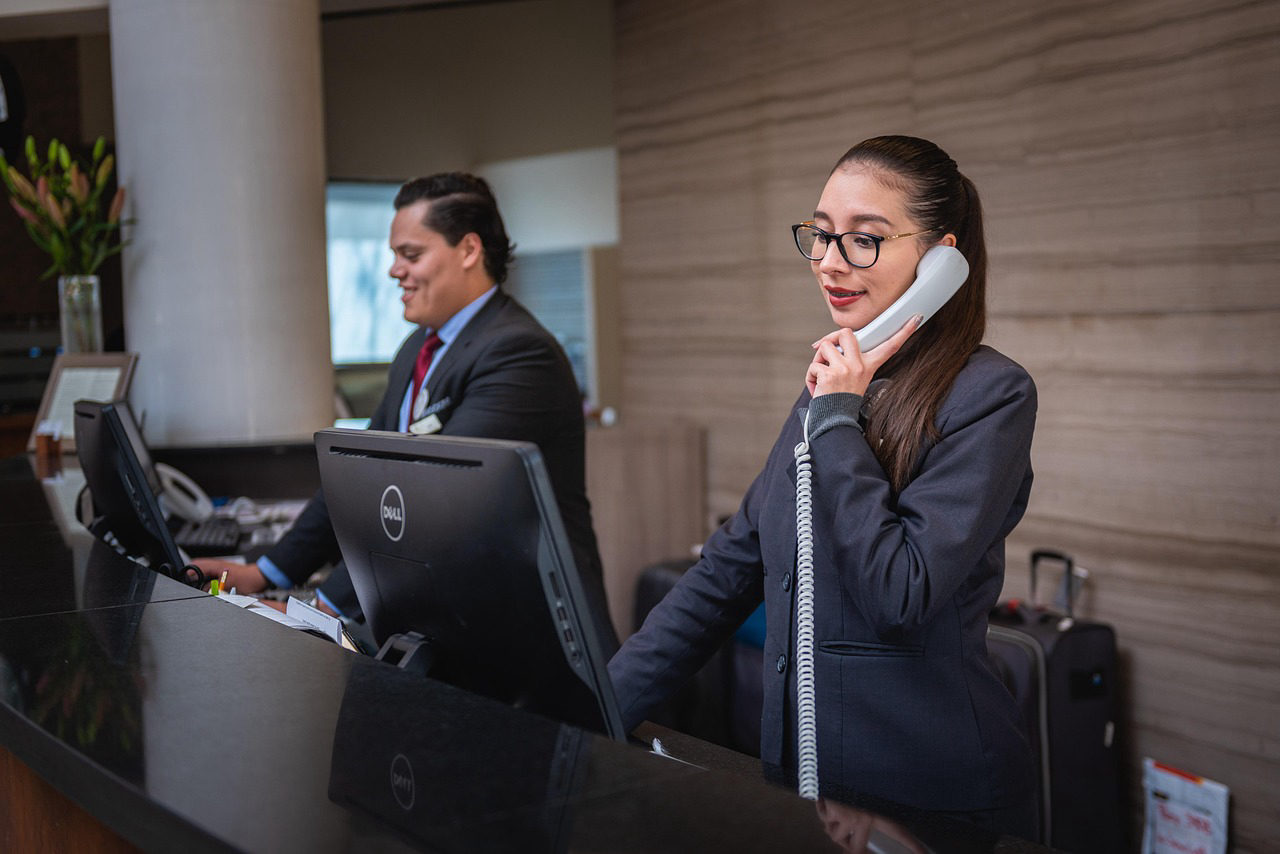 A professional receptionist answers a phone call at a modern front desk — representing a white label AI receptionist for digital marketing agencies in California